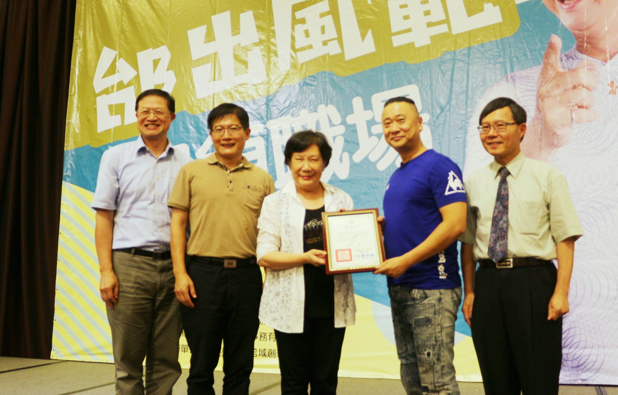 勞動力發展署長黃秋桂(中)致贈感謝狀給邰智源(藍衣者)，雲嘉南分署長劉邦棟(左2)、中正大學副校長郝鳳鳴(右1)、中正大學高齡跨域創新研究中心策略長方清輝(左1)都到場聆聽