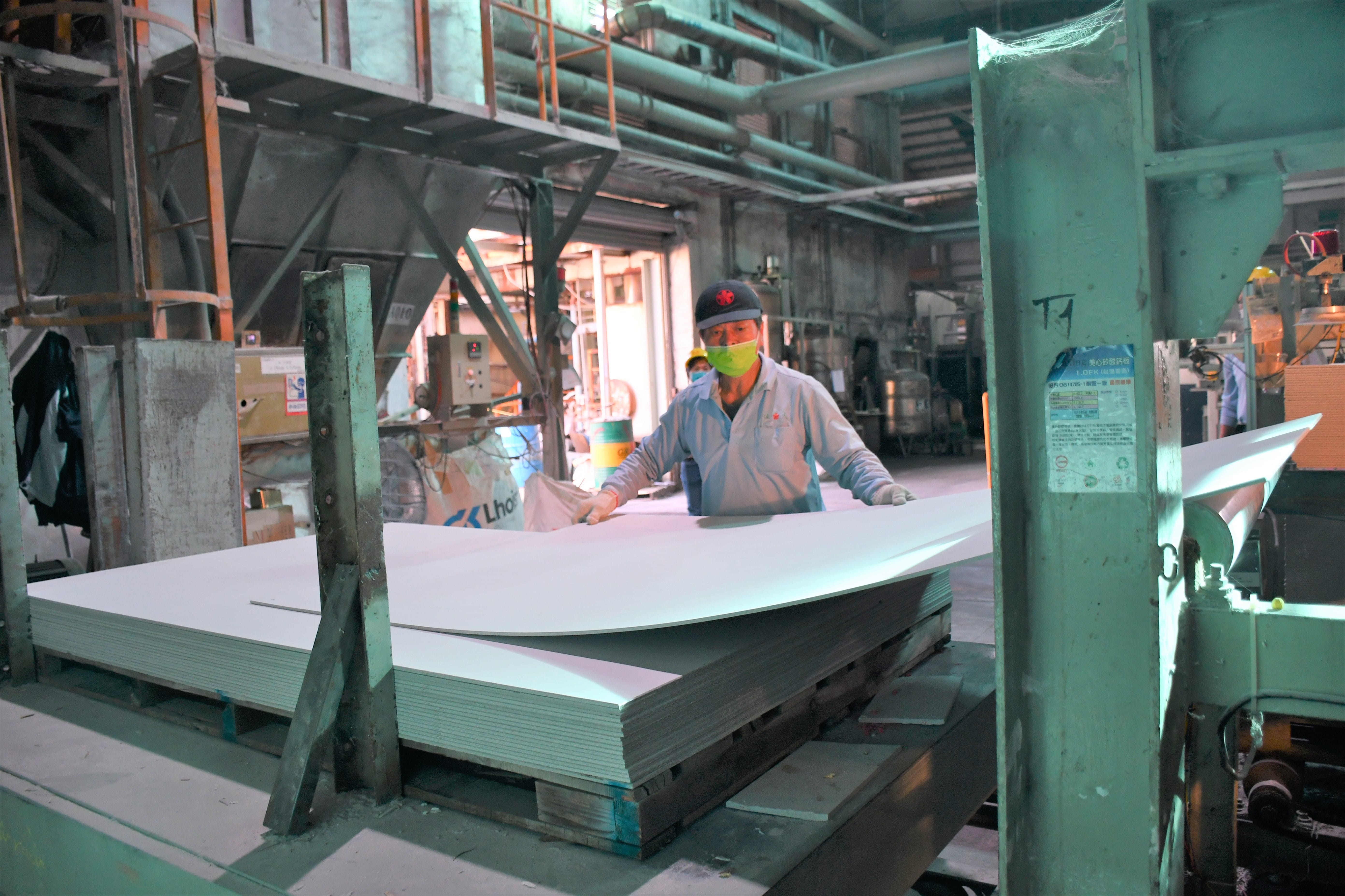 佳大建材公司產線人員透過勞動部「中高齡職務再設計」增購電動油壓平台，改善過去須人工蹲下起身放置矽酸鈣板的作業流程。