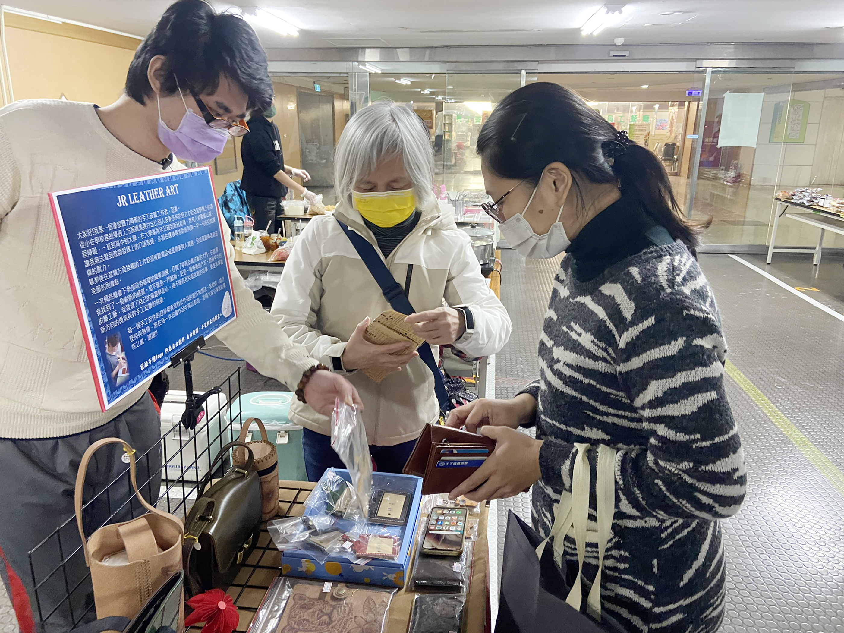 聽障者小冠(左)克服聽力與心理障礙，擺攤直接與客人面對面溝通說明作品與創作理念，吸引許多客戶青睞。
